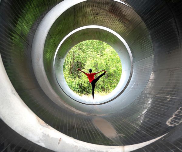 Silhouette of a person in a powerful yoga pose against a bright background.
